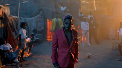 a man in a pink suit walking down a street