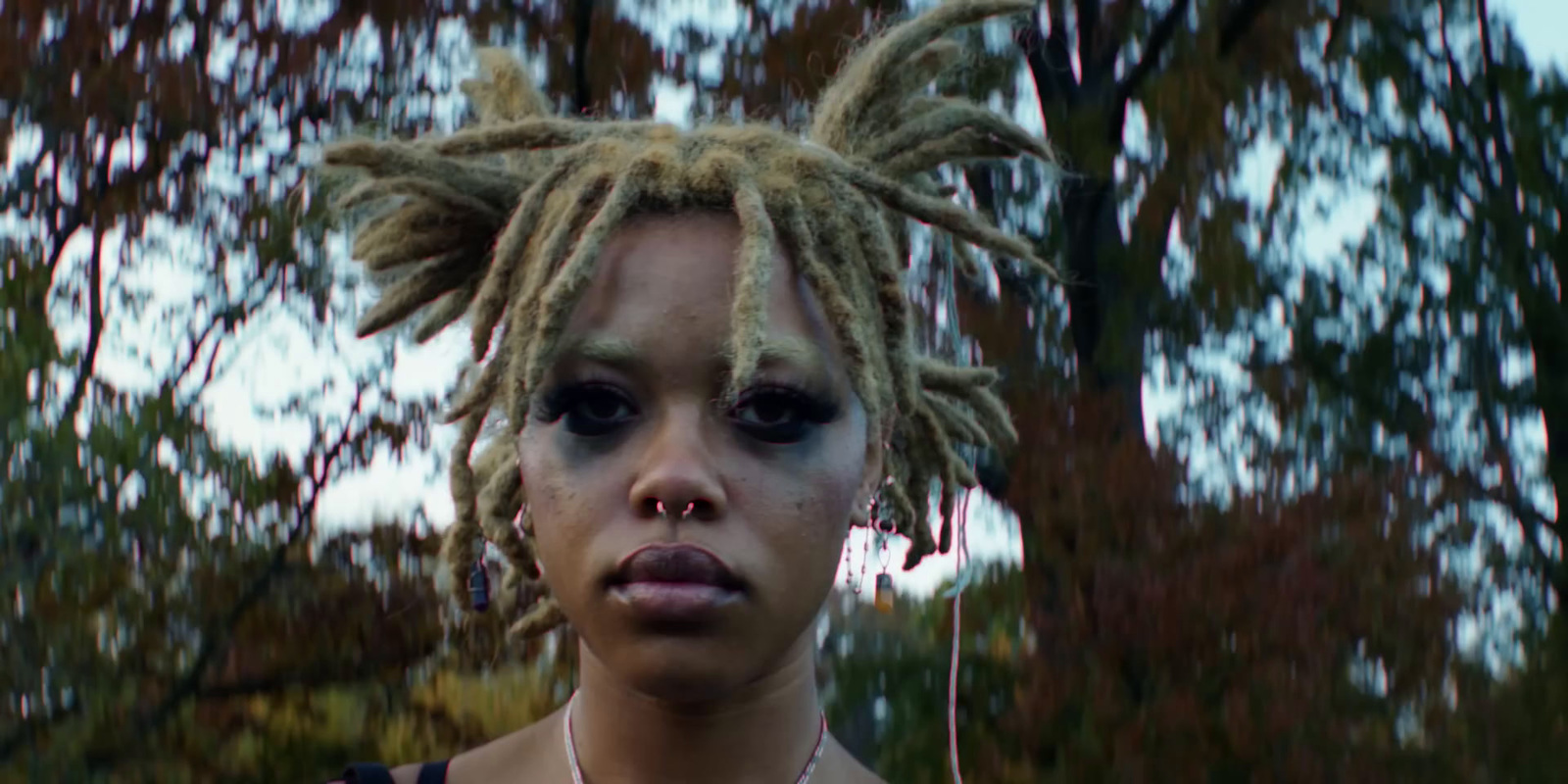 a woman with dreadlocks standing in front of a tree