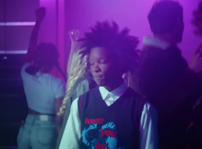 a young man with dreadlocks standing in front of a group of people