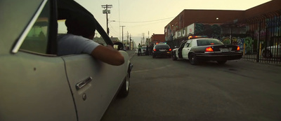 a group of cars driving down a street next to tall buildings