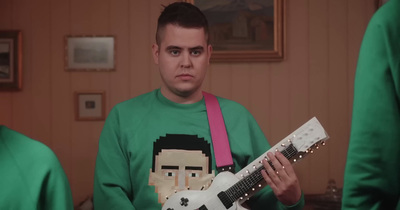 a man in a green shirt holding a white guitar