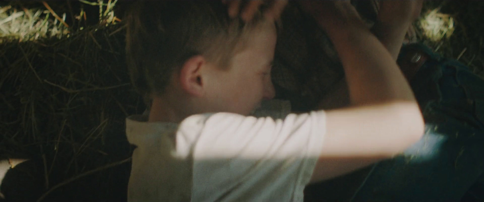 a young boy holding his hands up to his face