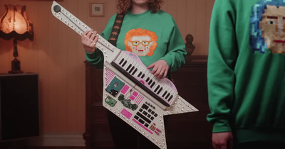 a girl in a green shirt holding a paper guitar