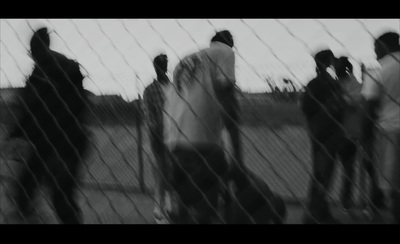 a black and white photo of a group of people behind a fence