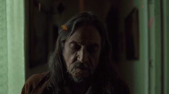 a man with long hair standing in a room