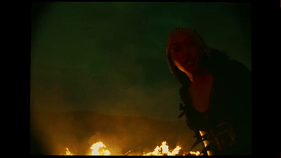 a woman standing in front of a fire in the dark