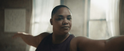 a woman in a tank top standing in front of a window