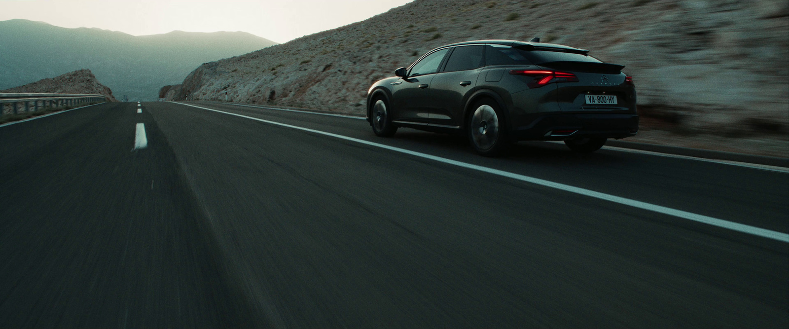 a black car driving down a mountain road