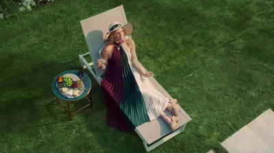 a woman in a dress and hat sitting on a lawn chair