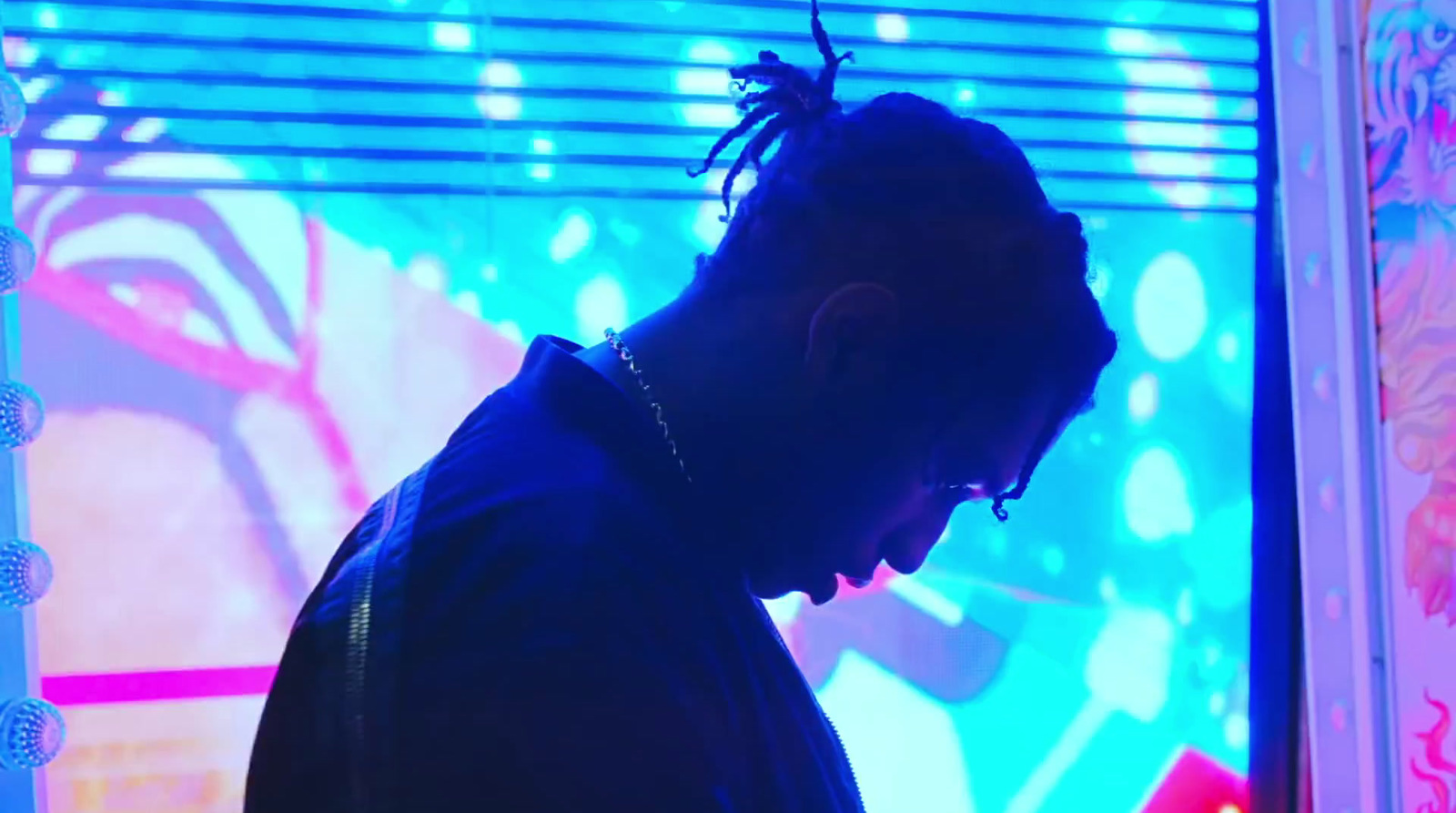 a man with dreadlocks standing in front of a tv