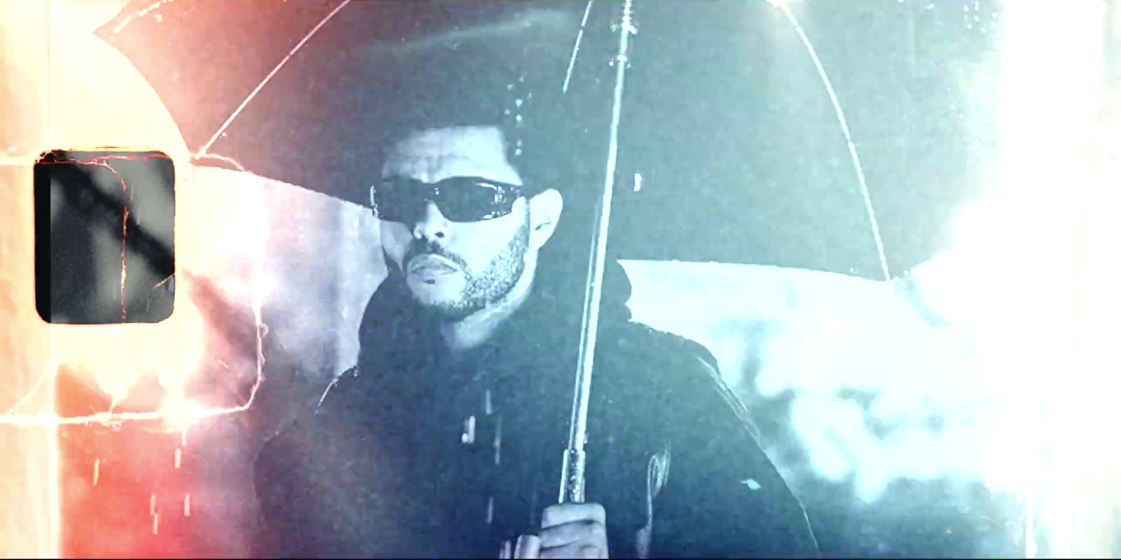 a man with sunglasses holding an umbrella in the rain