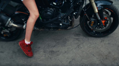 a woman sitting on a motorcycle wearing red shoes