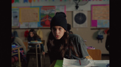 a young girl sitting at a desk in a classroom