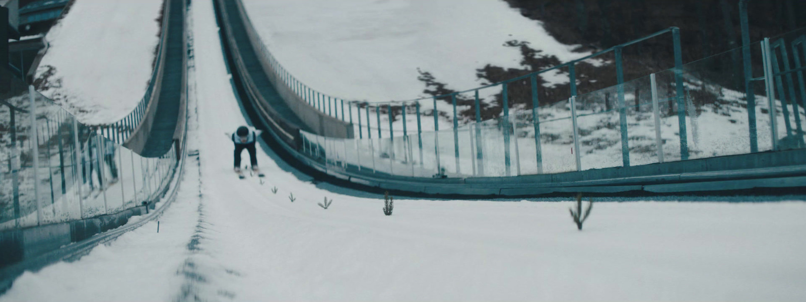 a man walking across a snow covered bridge