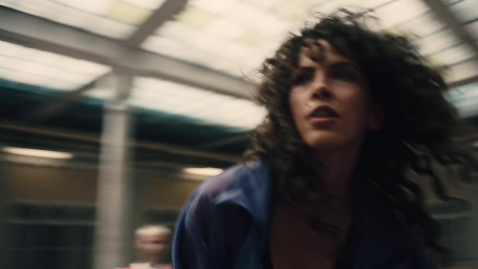 a woman with long hair walking through a train station