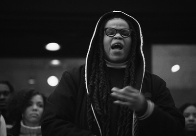 a man with dreadlocks standing in front of a group of people