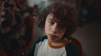 a young boy sitting in a chair with a surprised look on his face