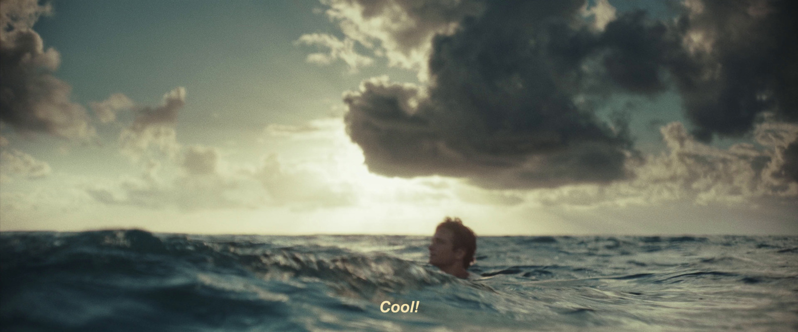 a man swimming in the ocean under a cloudy sky