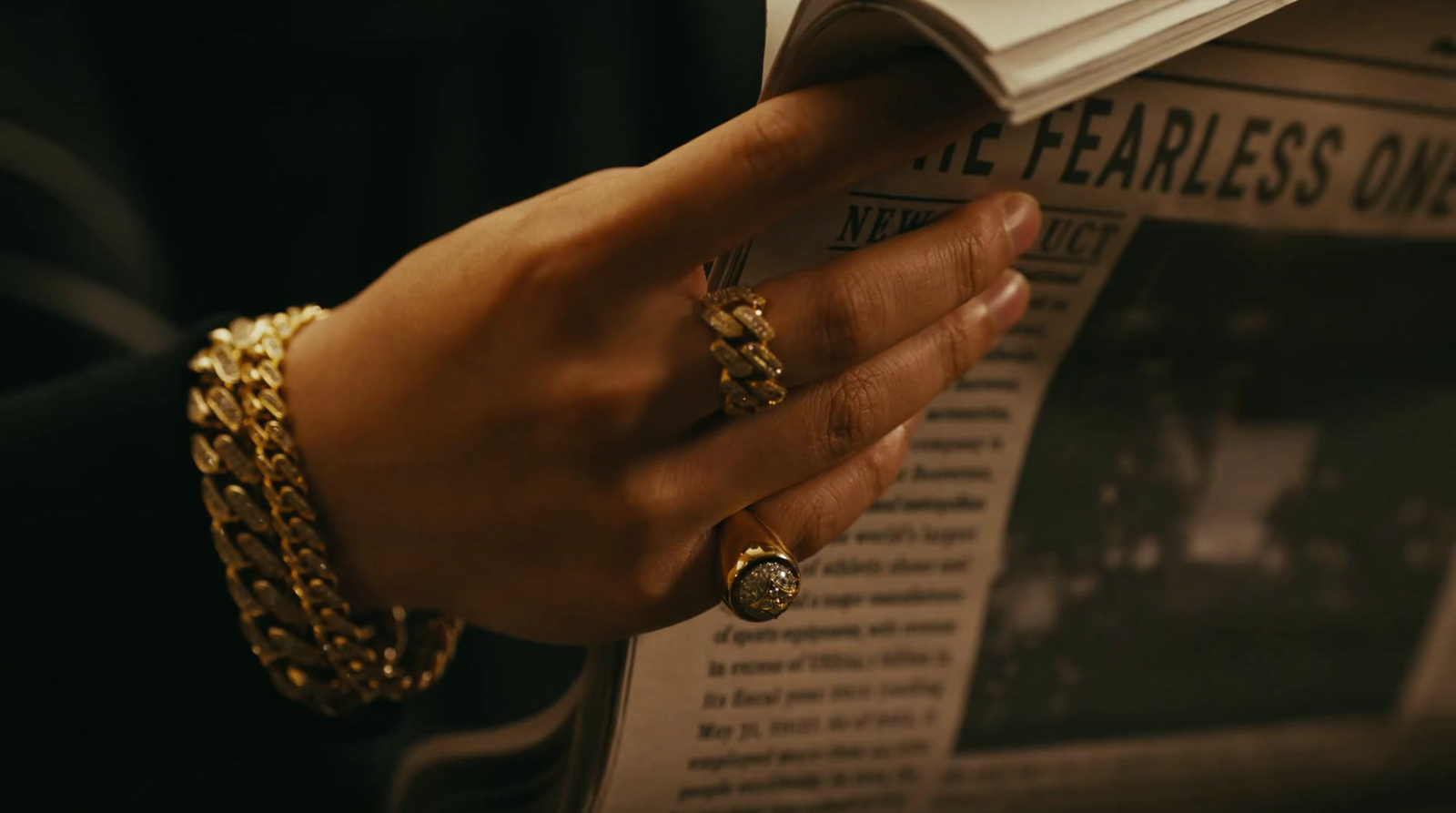 a person reading a newspaper with a gold ring on their hand