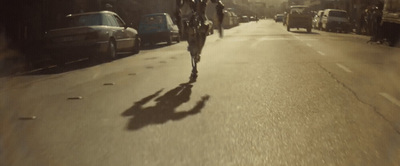 a man riding a bike down a street next to parked cars