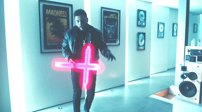 a man standing in a hallway holding a neon cross