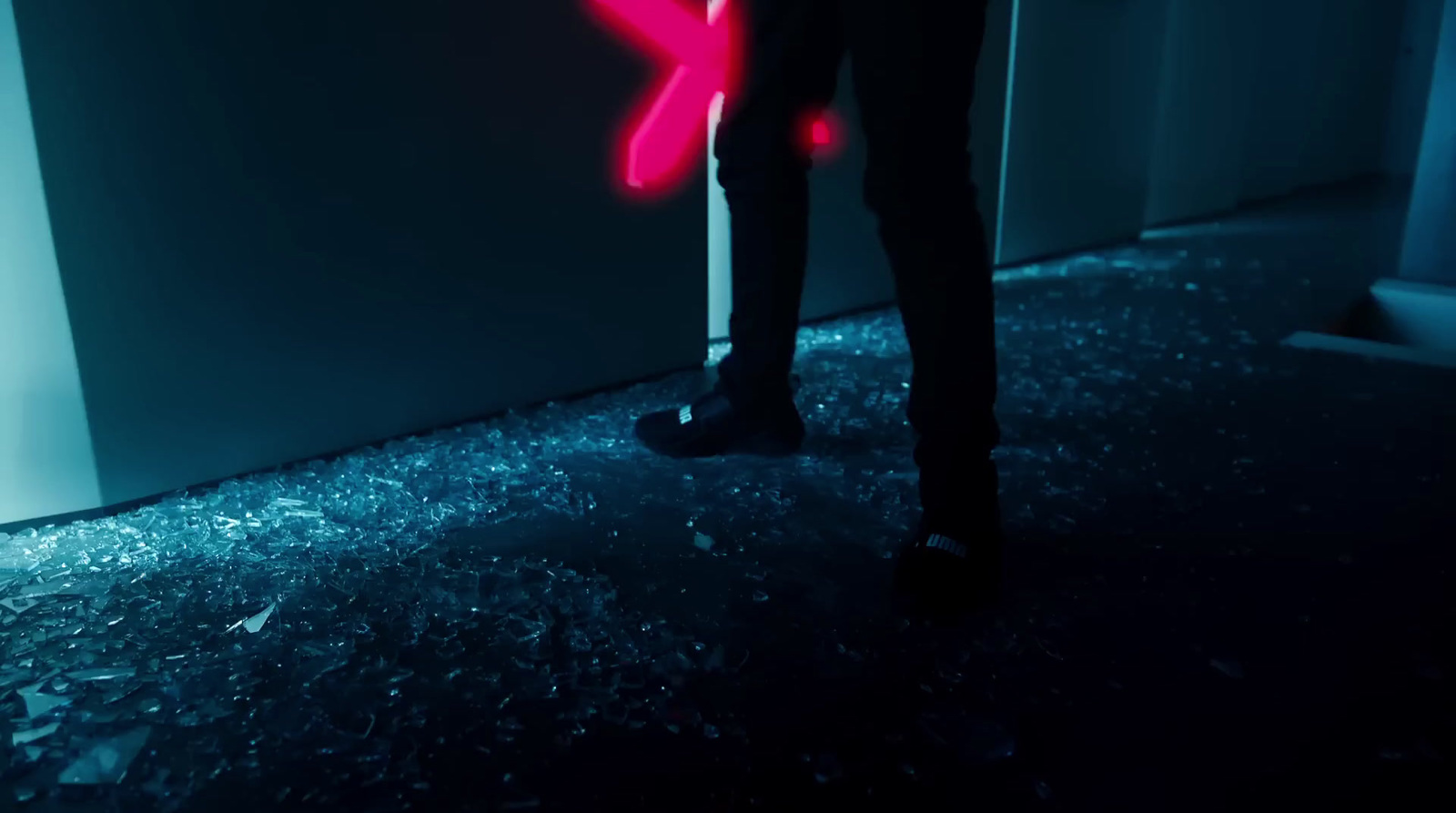 a person standing next to a wall with a neon pink x on it