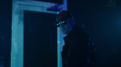 a man wearing sunglasses and a leather jacket in a dark room