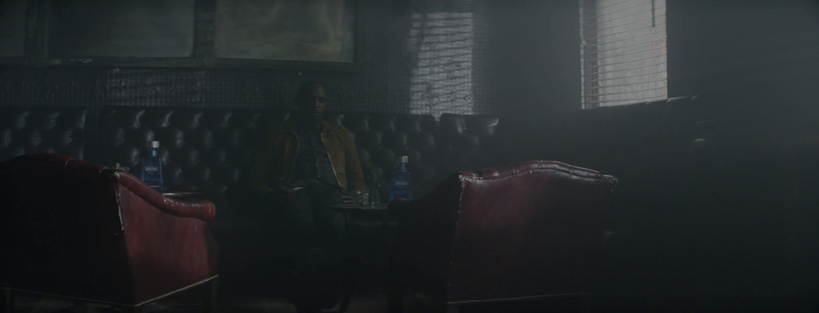 a man standing in a dark room next to a red chair