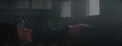 a man standing in a dark room next to a red chair