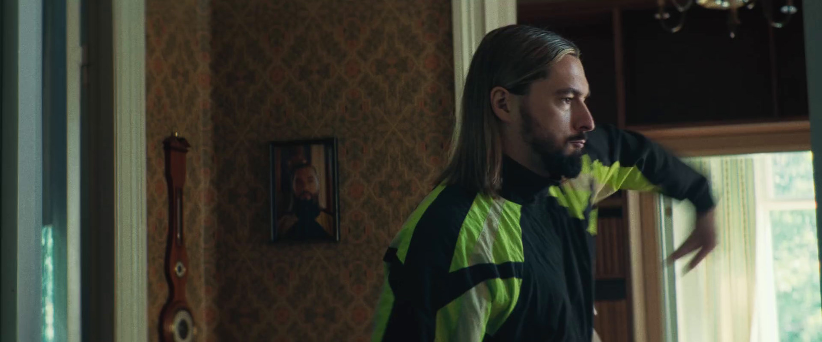 a man with long hair standing in a room