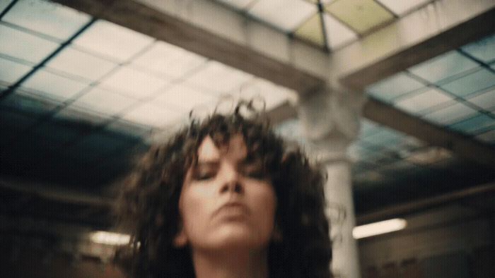 a woman with long hair standing under a glass roof