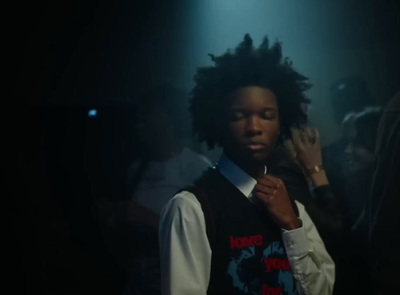 a man with dreadlocks standing in a dark room