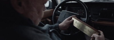 a man sitting in a car holding a piece of paper