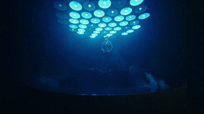 a person standing under a blue light in the dark