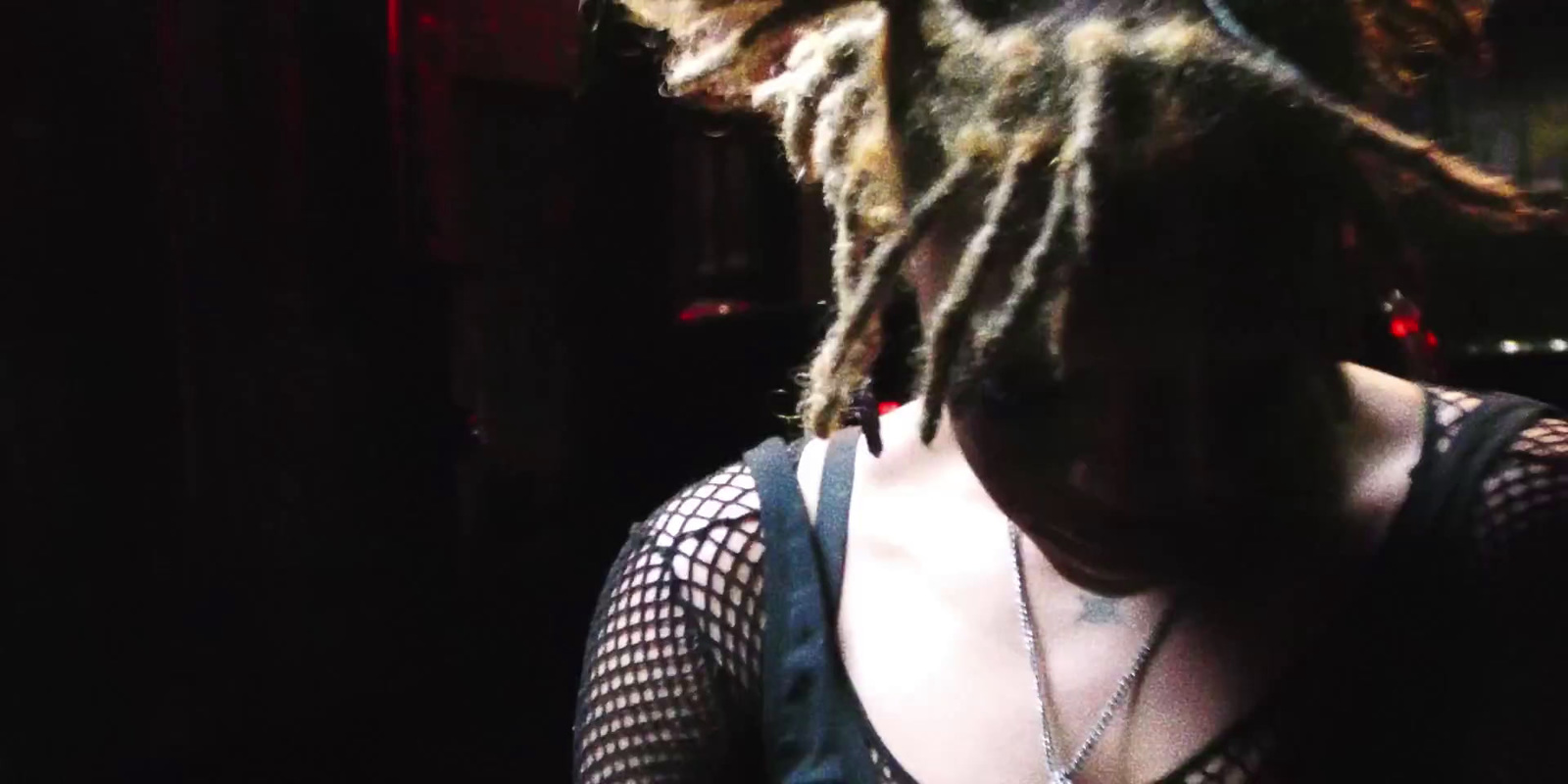 a woman with dreadlocks standing in a dark room