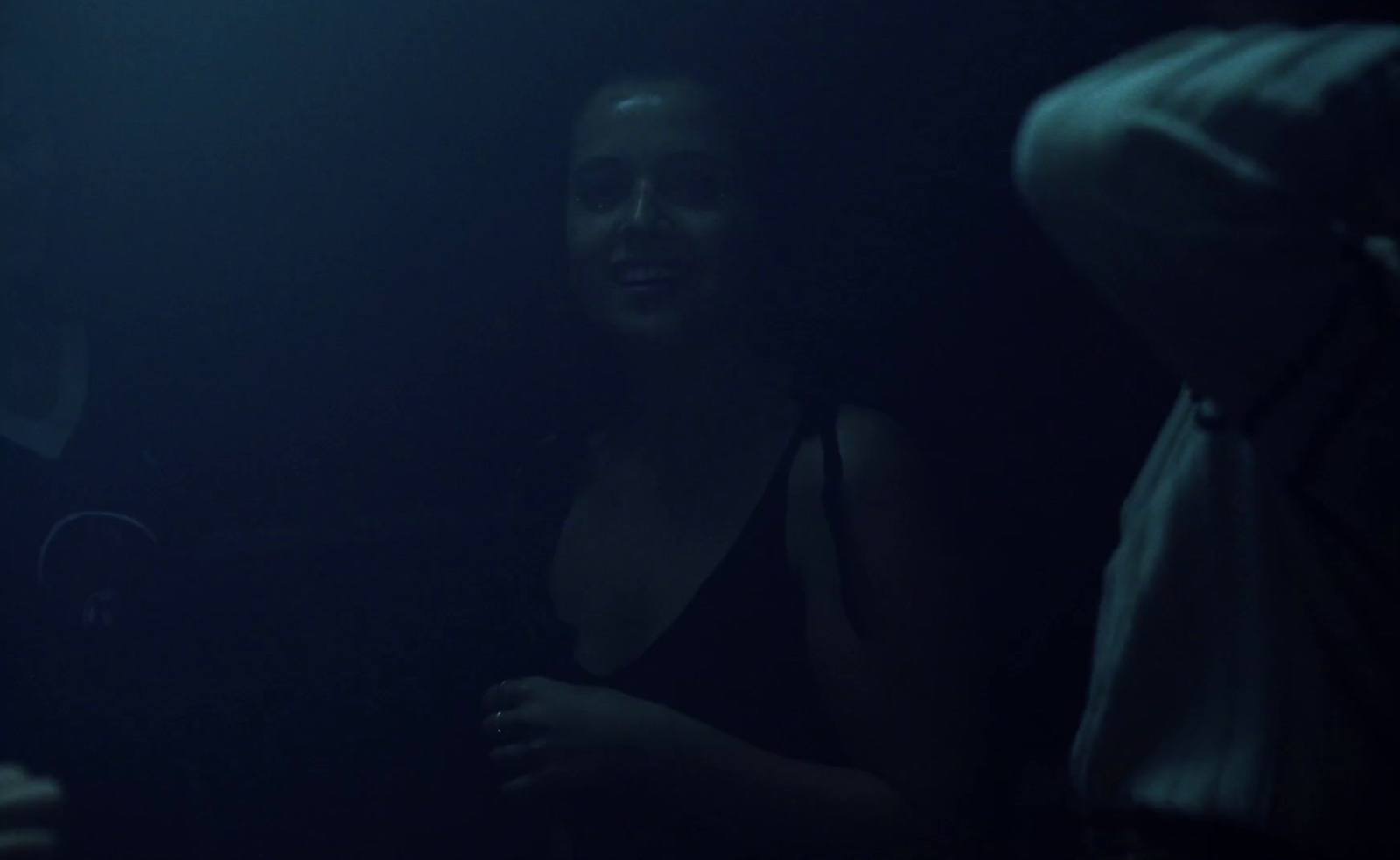 a woman standing in a dark room next to a man