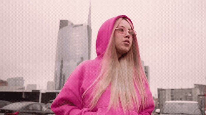 a woman in a pink hoodie standing in a parking lot