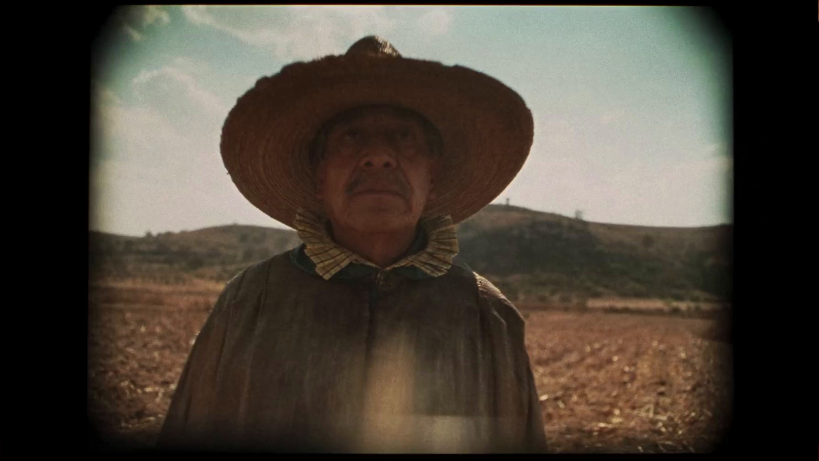 an old woman wearing a hat in a field