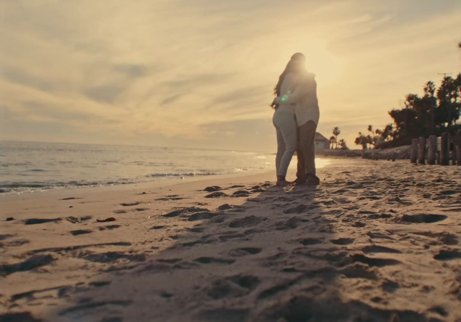 a woman standing on top of a sandy beach next to the ocean