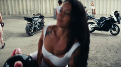 a woman in a white tank top standing next to a motorcycle