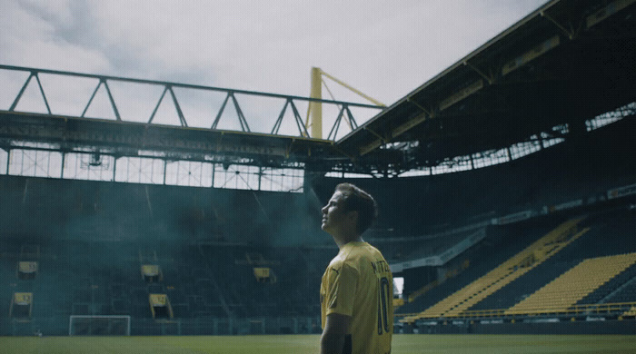 a man in a yellow shirt standing on a soccer field