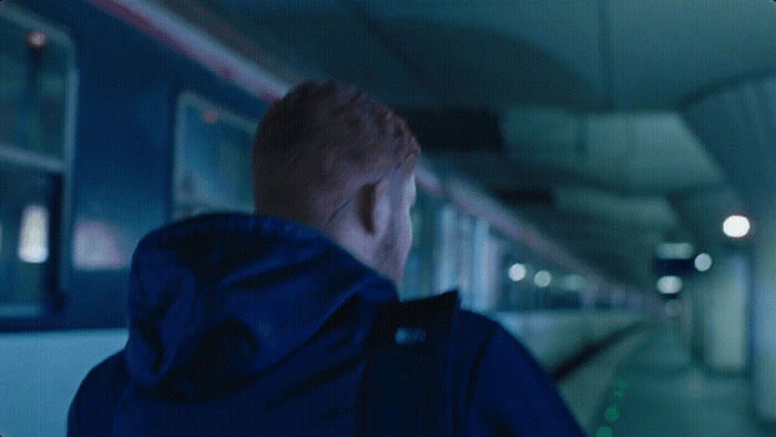 a man standing in a subway station looking out the window