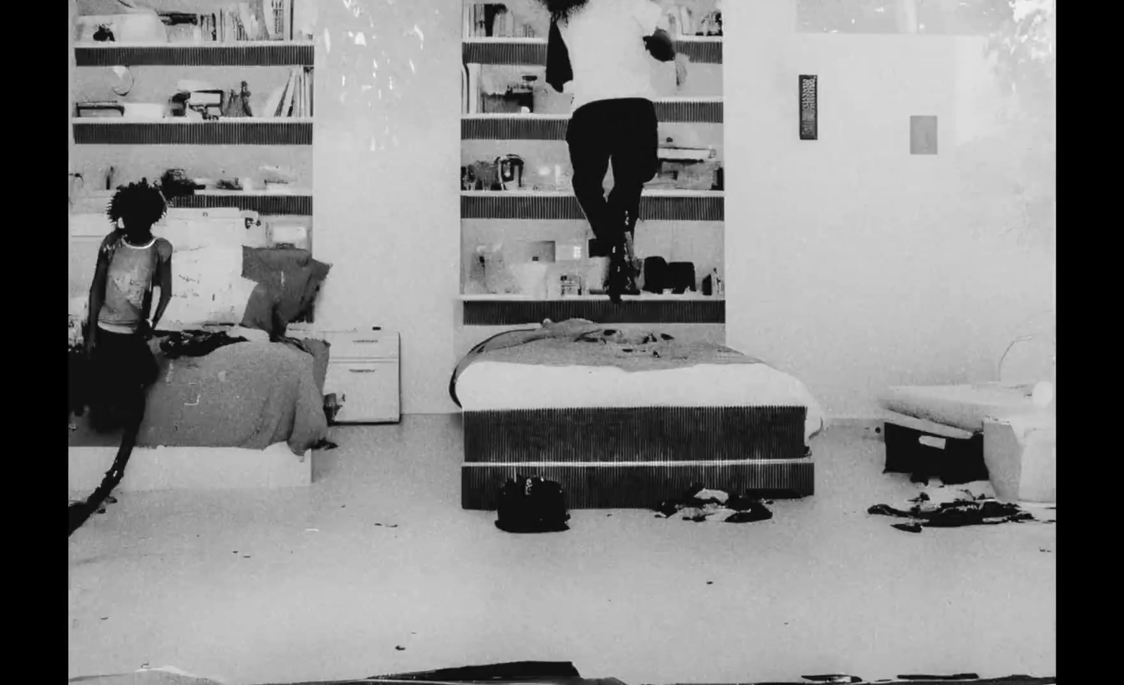 a black and white photo of a woman hanging on a bed