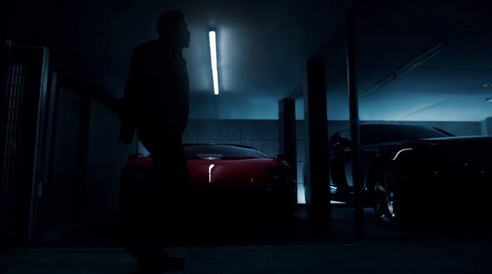 a man standing next to a red car in a dark garage