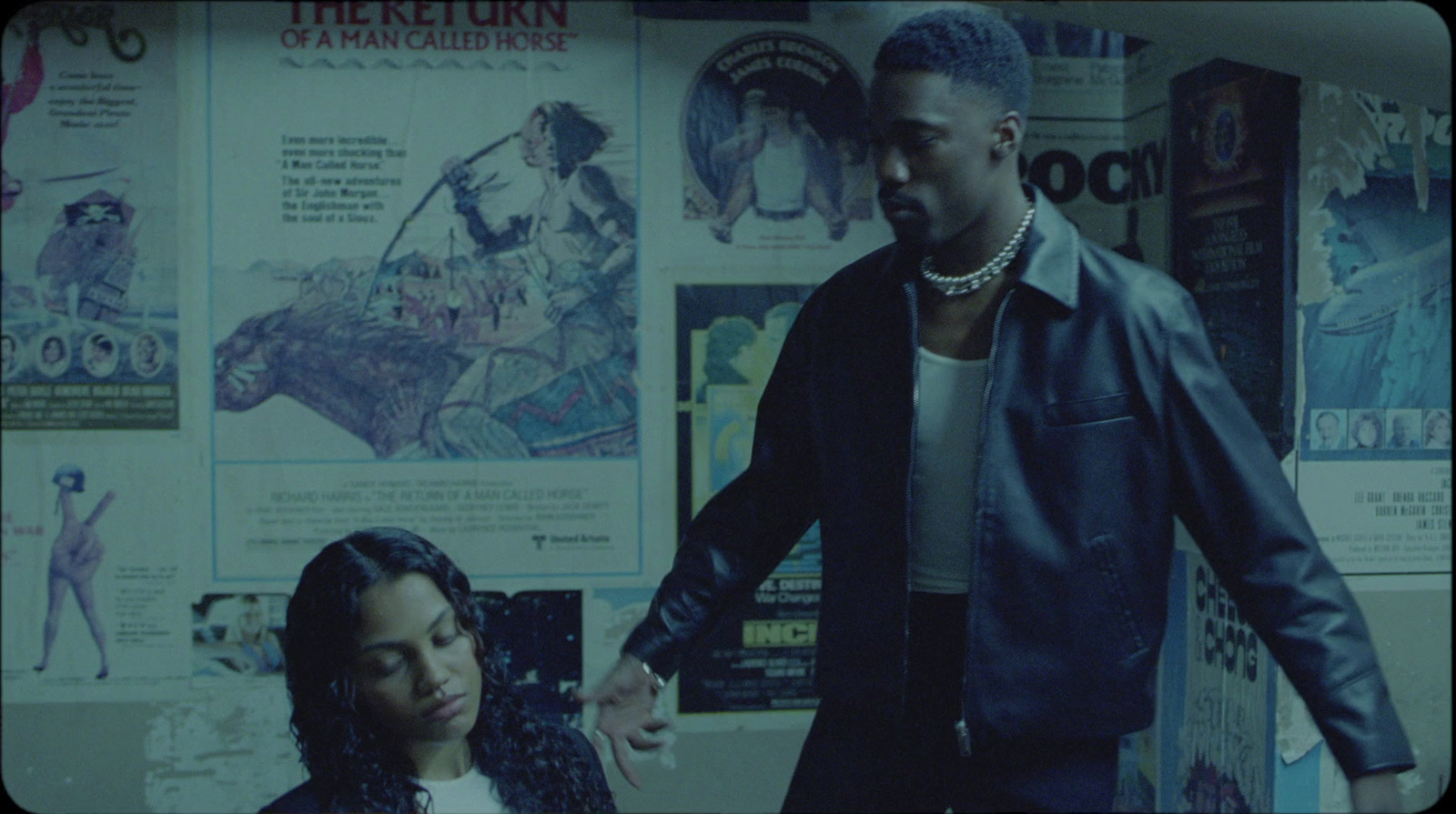 a man and a woman standing in front of a wall covered with posters