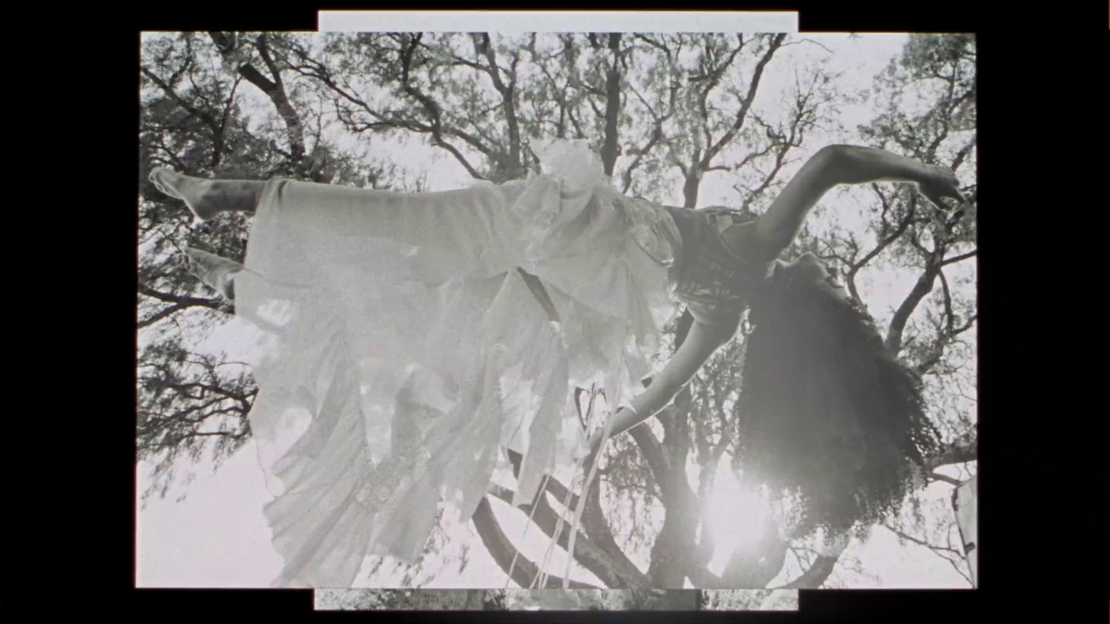 an old photo of a ghost hanging from a tree