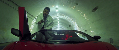 a man standing next to a red car in a tunnel