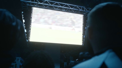 a person watching a soccer game on a big screen