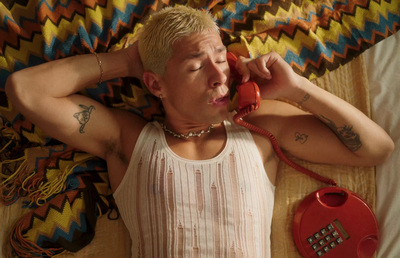 a man laying on a bed talking on a phone