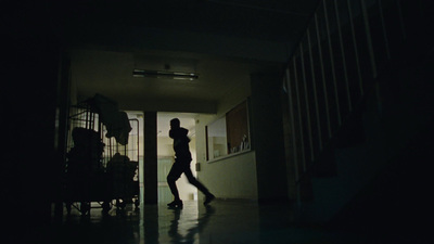 a woman walking down a hallway in the dark